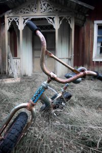 gammal barncykel framför gammal stuga